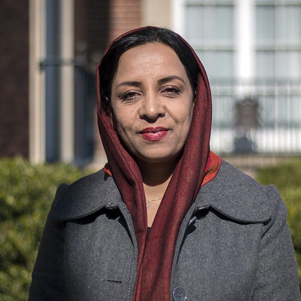 Portrait of a woman wearing a headscarf and gray coat, celebrating Women of Courage.