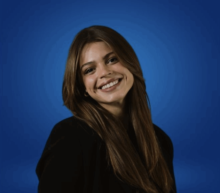 Photo of Isabella Berkeley, smiling with long brown hair wearing a black blazer